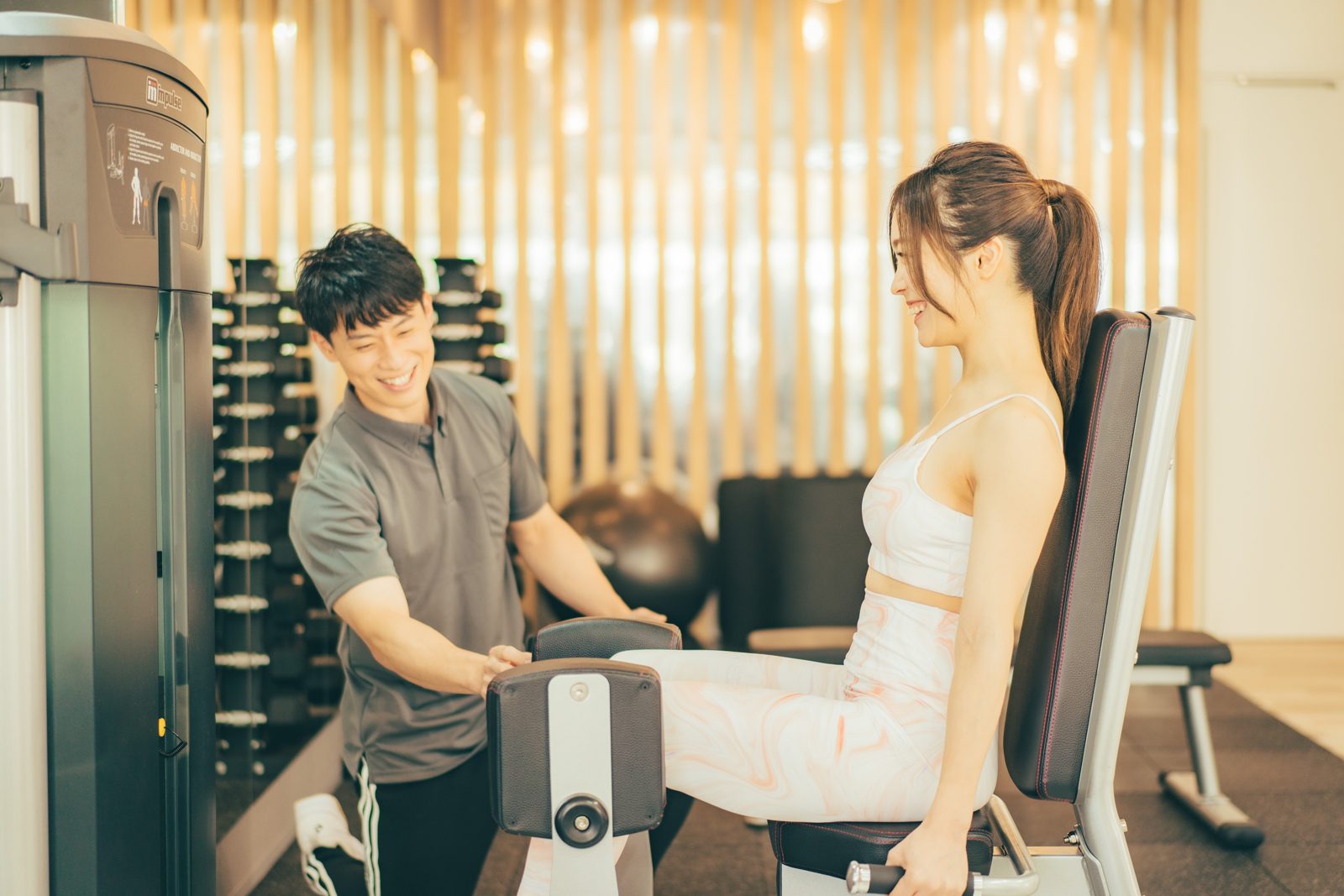 トレーナーに見守られながらトレーニングする女性